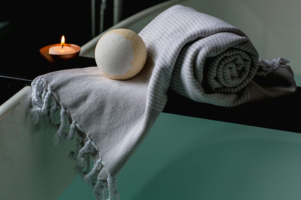 hidroterapia para el insomnio Vela encendida junto a una toalla y elementos de baño, representando un ambiente de hidroterapia relajante.
