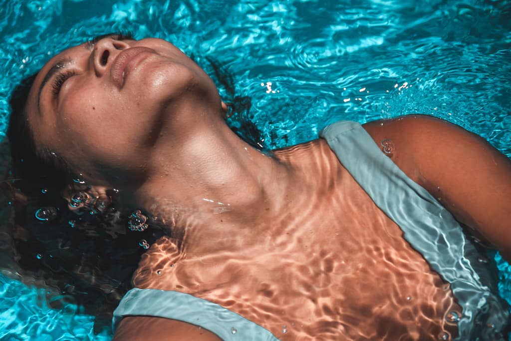 WATSU: Hidroterapia y Alivio Emocional Mujer flotando boca arriba en agua turquesa experimentando relajación profunda y sostén emocional durante una sesión de terapia WATSU.