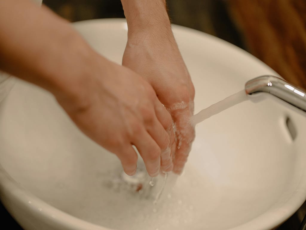 Lavado-de-Manos-Estimulo-Termico Persona dejando correr agua fría sobre sus manos y muñecas para aliviar la fatiga mental.