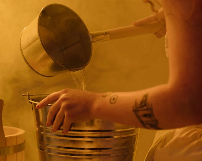 agua caliente para fomentos Persona preparando agua caliente en un recipiente metálico para una sesión de hidroterapia con fomentos.