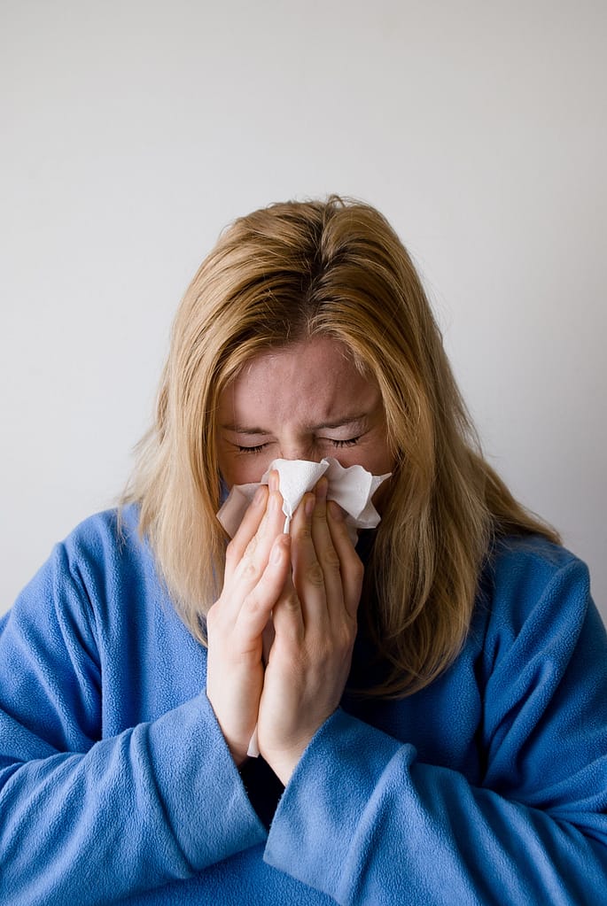 Alivio de pólipos nasales - Bio-Yin Mujer con congestión nasal usando un pañuelo, posible síntoma de pólipos nasales.